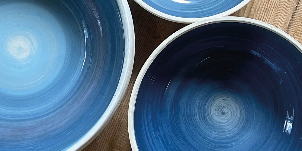 Tre blå keramikskålar på ett trägolv med texten 'Prova på: Keramik' i hörnet.