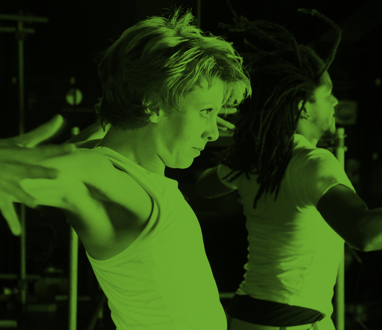 Två personer dansar energiskt med utsträckta armar, belysta av grönt ljus.