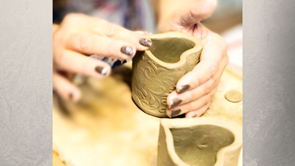 Två händer som drejar en hjärtformad kruka i en keramikverkstad