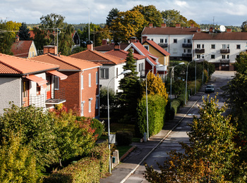 En lugn bostadsgata med radhus och gröna träd i ett villaområde under hösten.