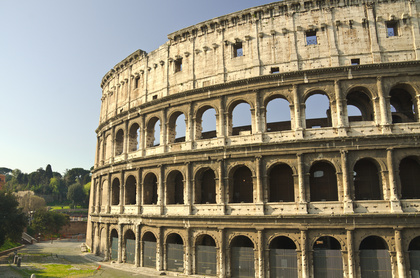 Närbild av Colosseum i Rom, en antik amfiteater med flera valvbågar och stenväggar under klar himmel.