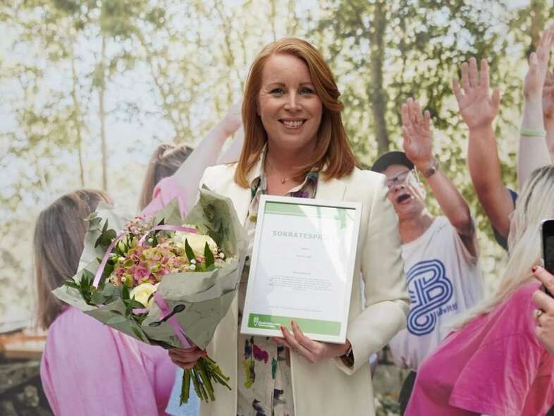 Annie Lööf med blommor och diplom i händerna.