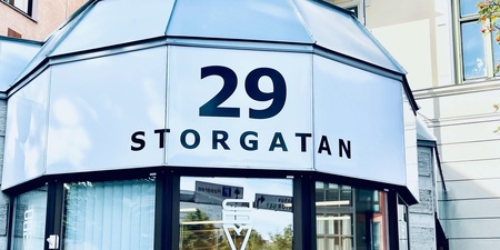 Ingång till byggnad med adressen 29 Storgatan, glasfönster och cykel utanför.