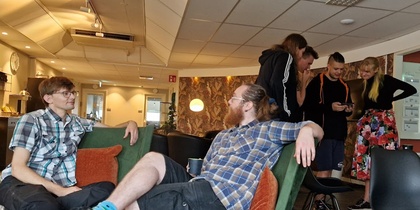 Sex personer umgås i ett modernt, ljust uppehållsrum med soffor och stolar.
