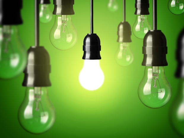 Flera hängande glödlampor mot grön bakgrund, en lampa lyser medan resten är släckta.