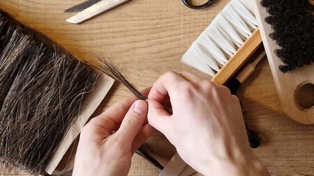 Händer binder borst på en träyta med verktyg och borstar runtomkring.