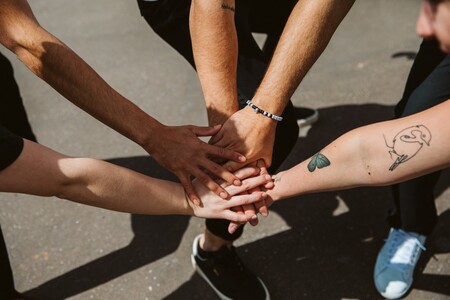 Fem personer räcker fram sina händer och lägger dem ovanpå varandra.