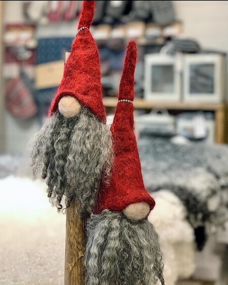 Två dekorativa tomtar med röda luvor och grått skägg står bredvid varandra inomhus.
