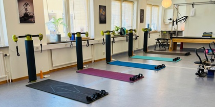 Ljust träningsrum med yogamattor, vikter och träningsutrustning uppställda för gruppträning.