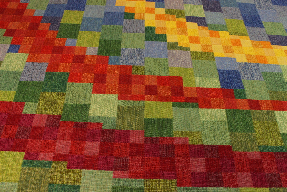 Färgglad matta med rutmönster i rött, grönt, blått och gult i abstrakt design.