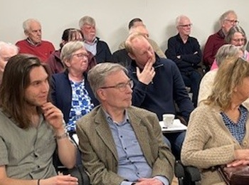 En grupp vuxna sitter i ett konferensrum och lyssnar på en presentation eller föreläsning.