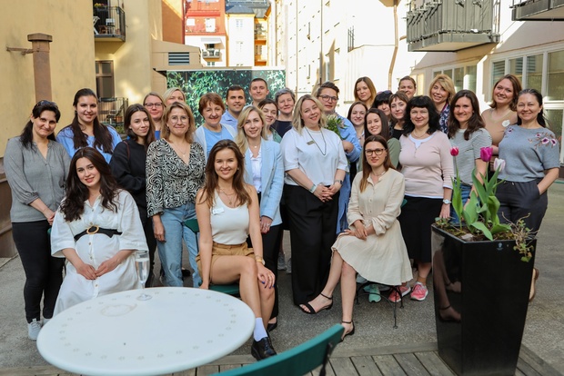 En grupp människor poserar tillsammans utomhus på en innergård, några sitter och andra står.