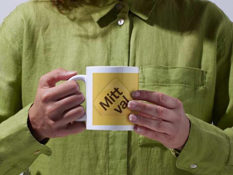 En person i grön skjorta håller i en kopp med en logotyp för Mitt val.