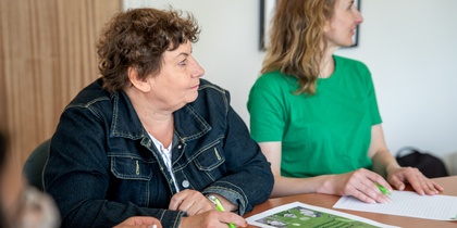 Två kvinnor sitter vid ett bord och antecknar under ett möte eller en workshop.
