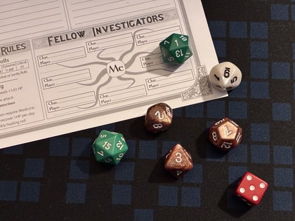 Flera tärningar och ett rollformulär för rollspel ligger på ett rutigt spelbord.