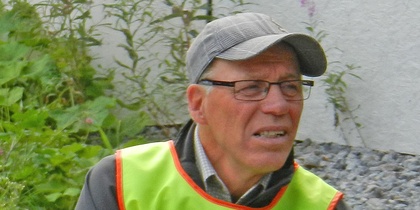 Person med reflexväst sitter vid ett bord utomhus med papper framför sig.