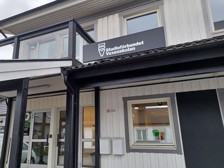 Entré till en vit byggnad med skylt för Studieförbundet Vuxenskolan ovanför dörren.