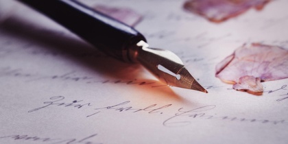 En närbild av en reservoarpenna på ett handskrivet brev med torkade blomblad.