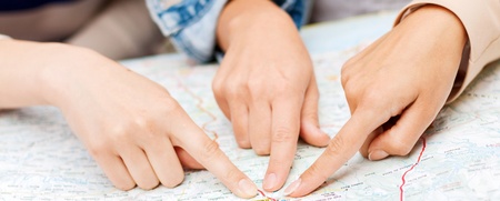 Två personer pekar med sina fingrar på olika platser på en papperskarta.