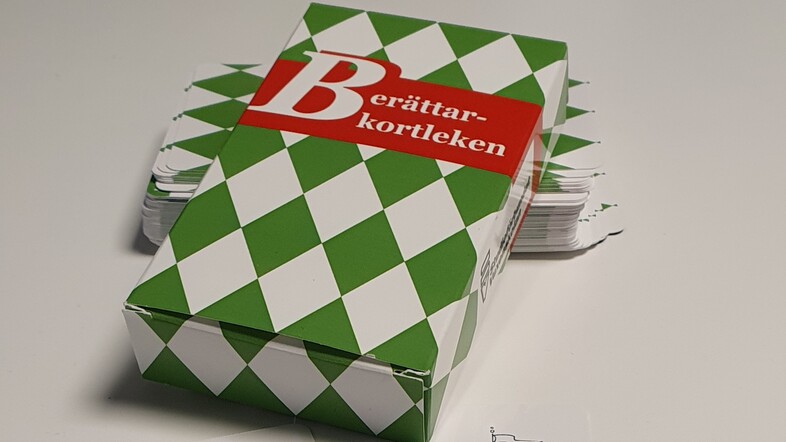 En kortlek i en grön och vit rutmönstrad ask med texten 'Berättarkortleken' på locket.