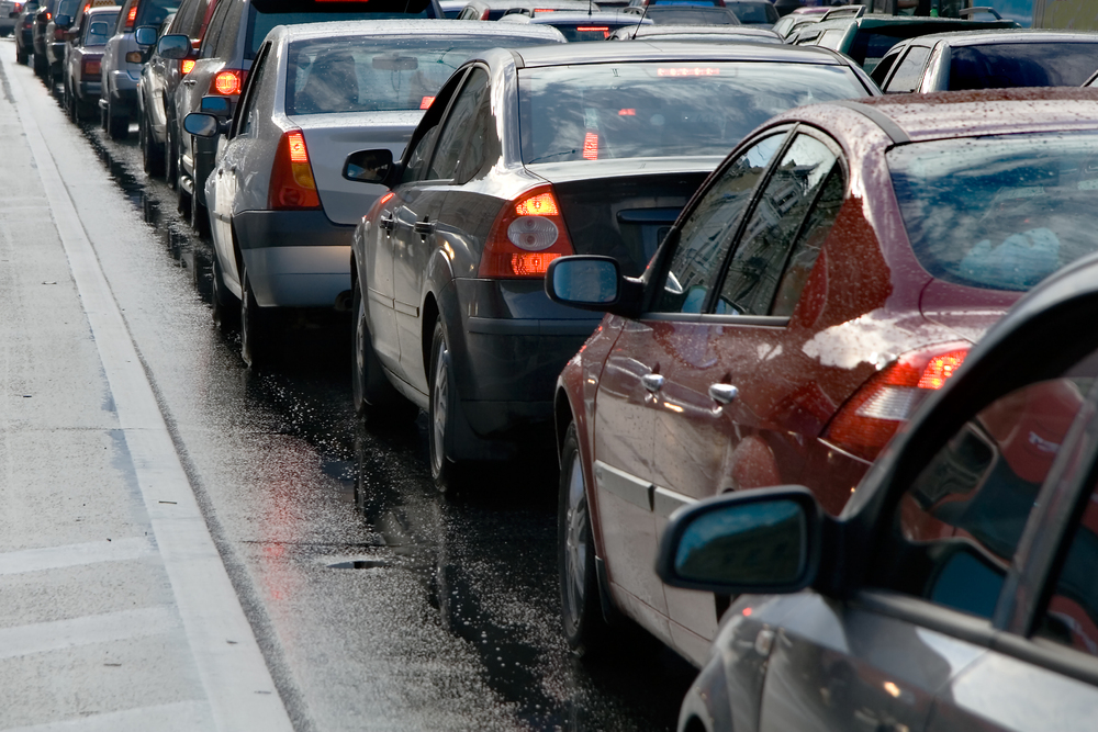 Bilkö på en våt väg, flera bilar står stilla i tät trafik.