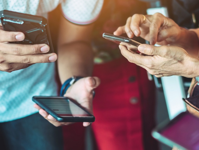 Flera personer håller och använder smartphones i närbild, fokus på händer och mobiler.
