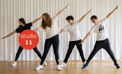 Fyra ungdomar dansar i en studio med vita gardiner och trägolv, alla sträcker ut armarna åt sidan.