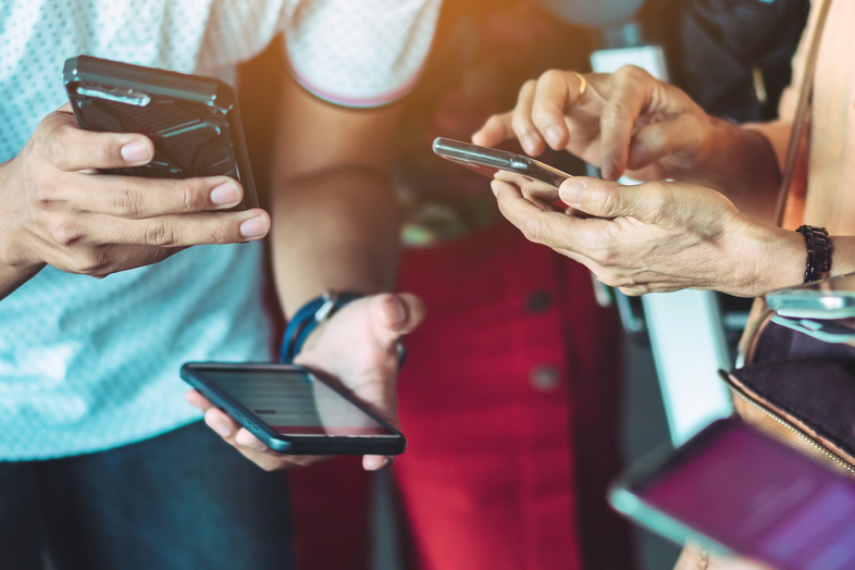 Flera personer håller och använder smartphones i närbild, fokus på händer och mobiler.