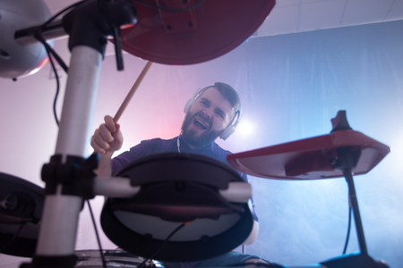 Man spelar trummor med hörlurar i en rökfylld studio, sedd underifrån.