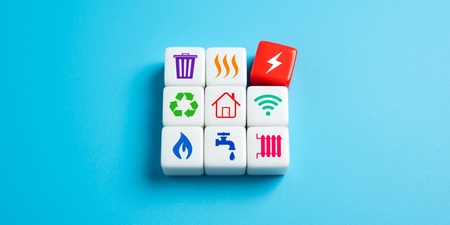 Nio kuber med ikoner för el, vatten, värme, återvinning och andra hushållstjänster på blå bakgrund.