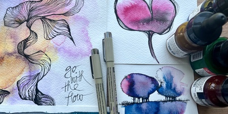 Akvarellmålningar med bläckpennor, färgflaskor och texten 'go with the flow' på ett papper.