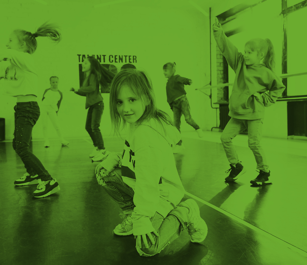 Barn dansar i en dansstudio med grönt filter över bilden. En flicka sitter på huk i förgrunden.