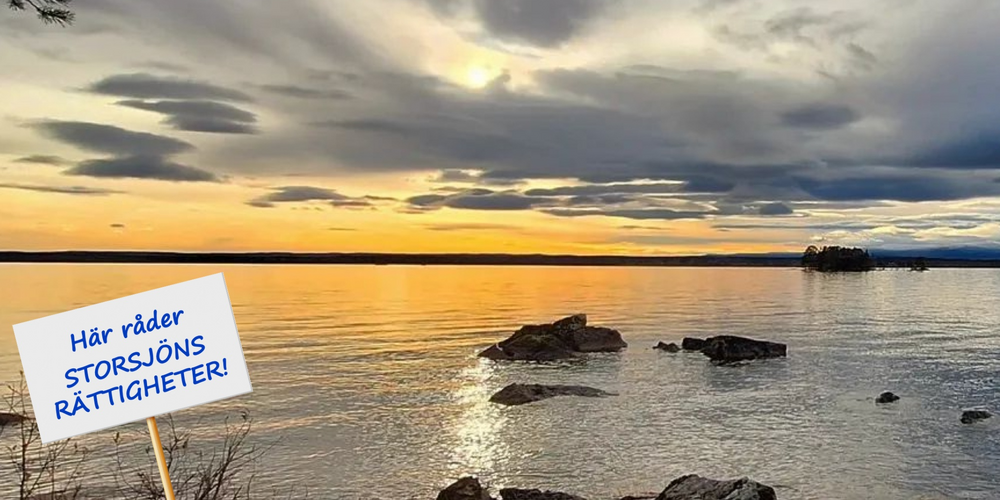 Solnedgång över en sjö med stenar i vattnet och en skylt som säger: Här råder Storsjöns rättigheter!