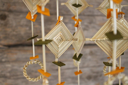 Närbild på en traditionell mobil av halm och färgat filt, hängande mot en trävägg.