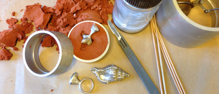 Utrustning och material för sandgjutning av smycken, inklusive sand, formar, verktyg och metallföremål.