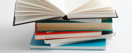 En hög med böcker där den översta boken är uppslagen och resten är stängda, mot vit bakgrund.