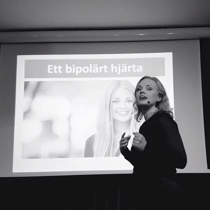 En person håller en presentation framför en projektor med texten 'Ett bipolärt hjärta'.