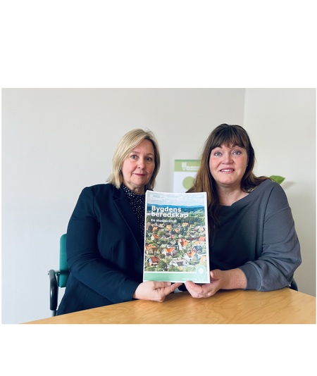 Två kvinnor sitter vid ett bord och håller upp en broschyr med texten 'Bygdens beredskap'.