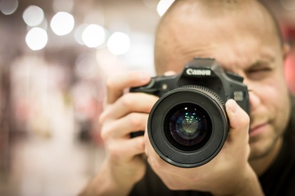 En person håller en kamera nära ansiktet och fotograferar mot kameran.