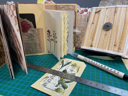 Ett skrivbord med handgjorda anteckningsböcker, linjal, kalligrafipenna och dekorerat papper.