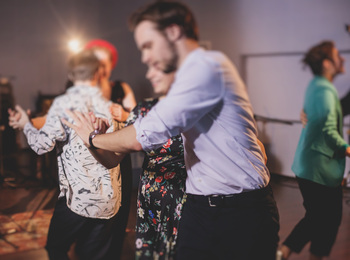 En grupp människor dansar tillsammans i ett rum med dämpad belysning.
