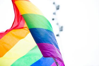 En regnbågsflagga vajar mot en ljus bakgrund, symboliserar HBTQ+-rörelsen.