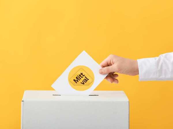 En hand lägger en röstsedel med texten 'Mitt val' i en vit valurna mot gul bakgrund.