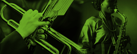 Två musiker spelar trumpet och saxofon, bilden har ett grönt filter.