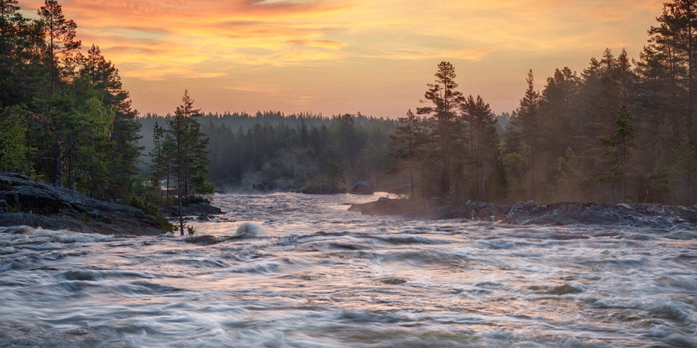 Omslag med en forsande älv i skogsmiljö vid solnedgång, texten 'Studiehandledning Vatten Land'.