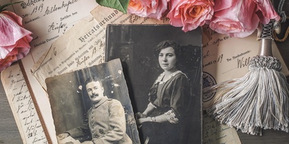 Gamla foton på en bädd av utländska tidningar och rosa rosor.
