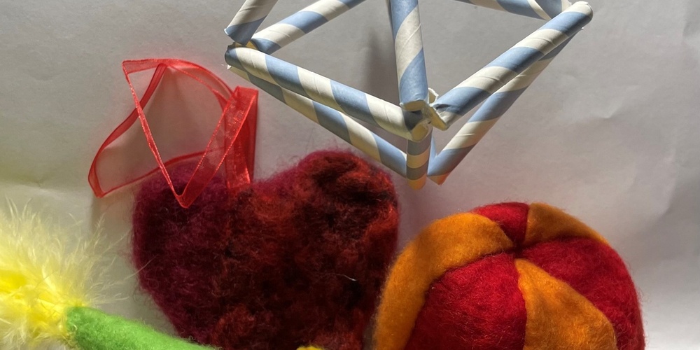 Färgglada handgjorda prydnader: en grön fågel, ett rött hjärta, en röd-gul boll och en geometrisk mobil av sugrör.