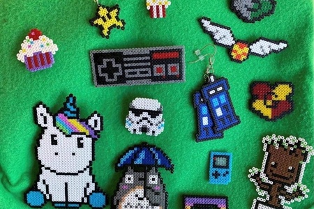 Flera pärlplattor föreställande figurer som enhörning, stormtrooper, Tardis och spelkontroll på grön bakgrund.