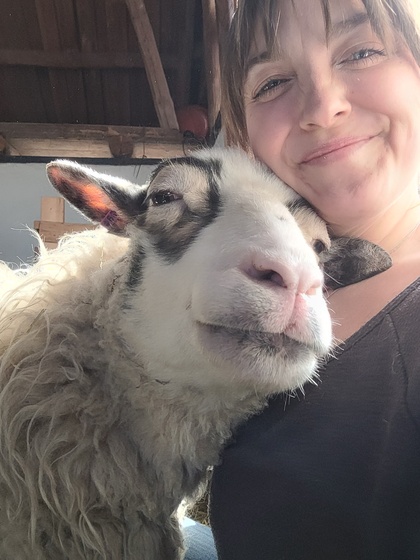 En kvinna tar en selfie med ett får, båda ser glada ut och är nära varandra.