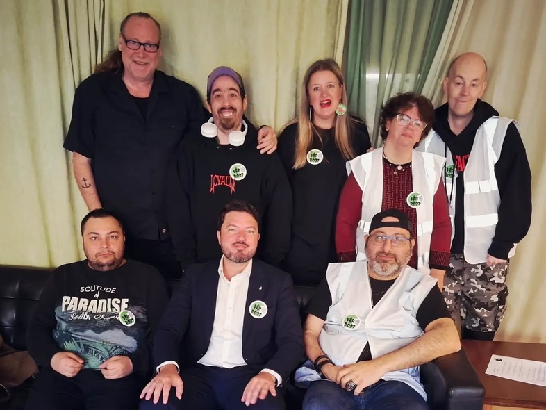 Gruppfoto av åtta personer, några sitter i soffa och andra står bakom, alla har ansikten suddade.